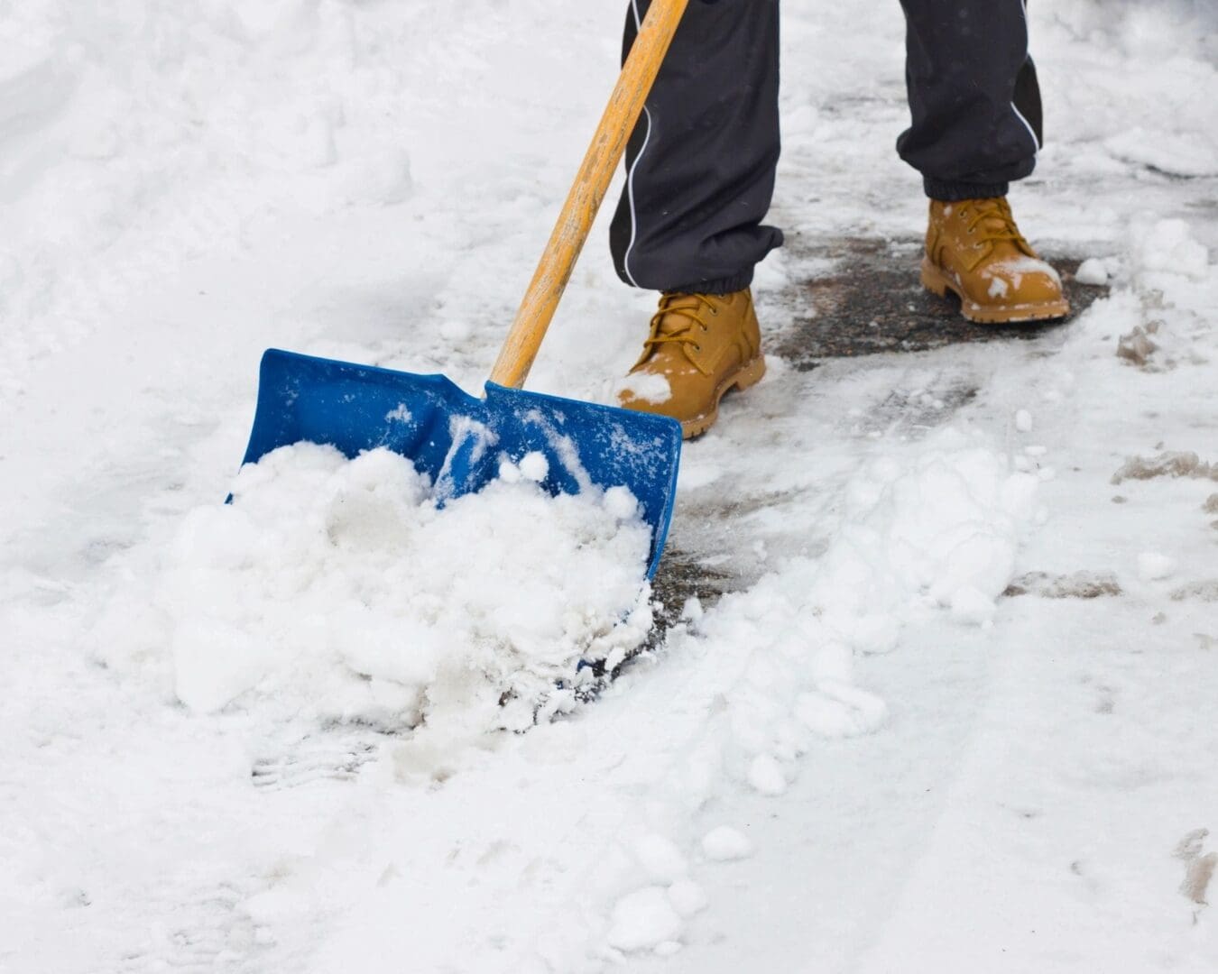 A person shoveling snow with a blue shovel.
