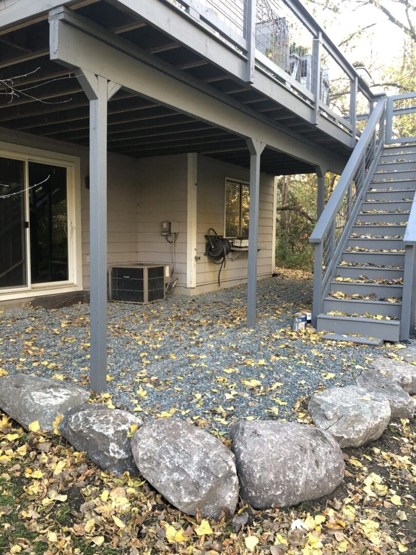 A patio with stairs and rocks in the yard.