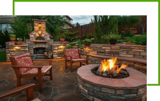 A fire pit with chairs around it and bushes in the background.