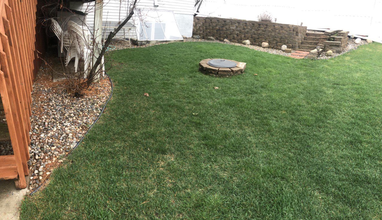 A backyard with grass and rocks in the middle of it.